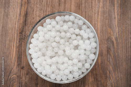 hydrogel white balls in glassware on wooden board. artificial moisture-absorbing material that contributes to accumulation and preservation of moisture. used for planting plants or children games