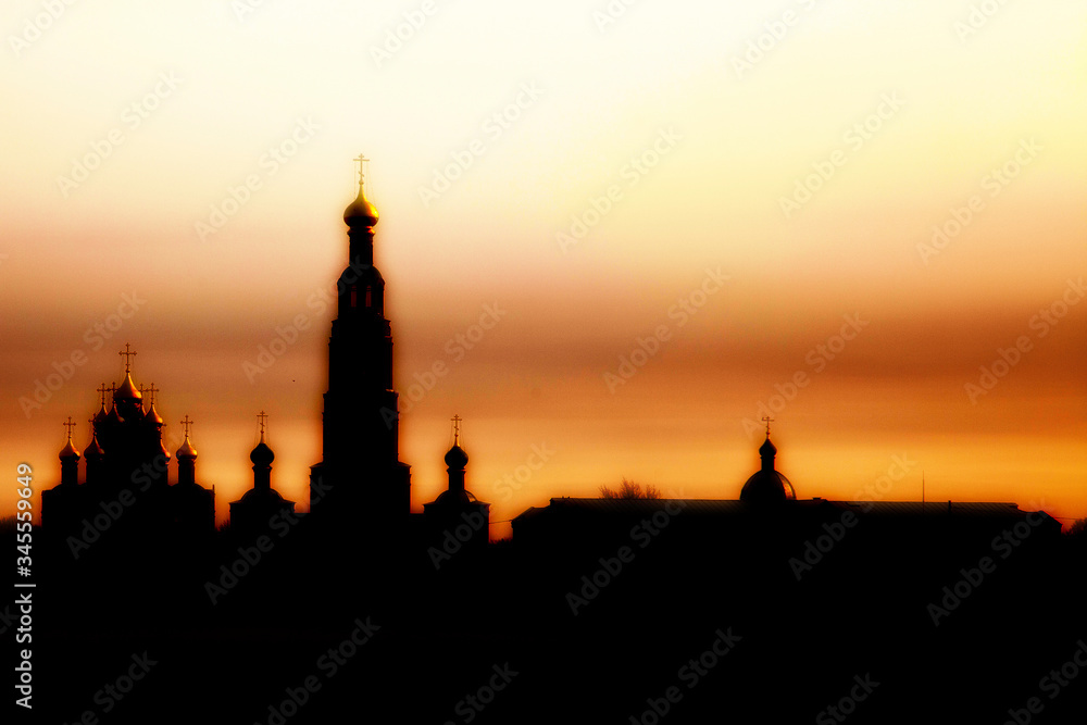 The silhouette of an Orthodox monastery and church at sunset