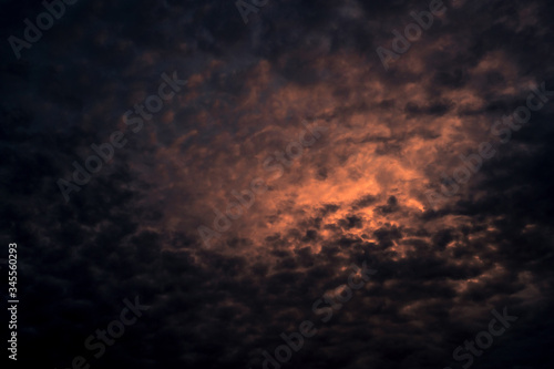 Red light of sun in dark cloudy sunset sky. Dramatic sky with beautiful pattern of fluffy clouds. Mental power or psychic power background. Power of nature. Exotic cloudscape. Climate change concept. photo