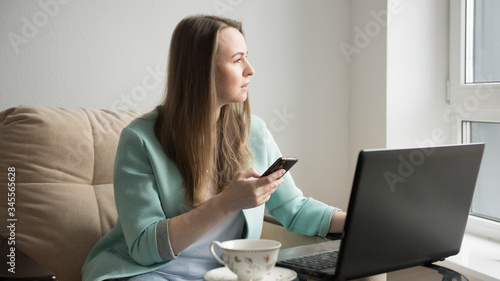 a girl is talking on the phone next to a laptop