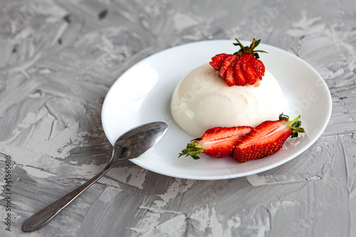 italian dessert panna cotta with fresh strawberries and a banana on a grey concrete background