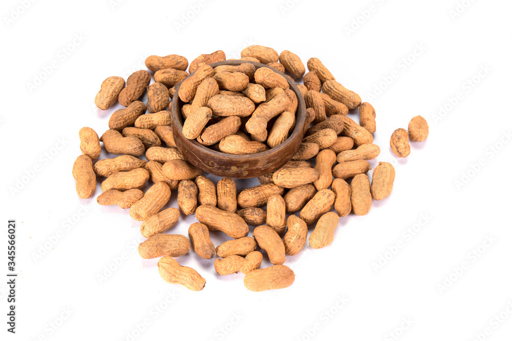 Groundnuts kept in a wooden bowl on top of some scattered ones.
Groundnuts kept in a wooden bowl on top of some scattered ones.