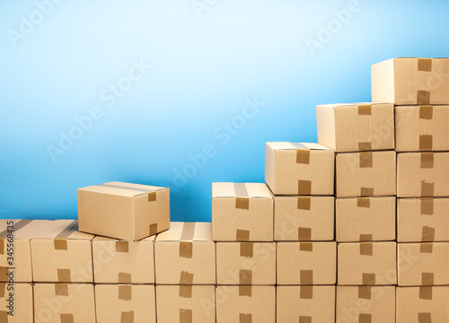 Cardboard boxes steps up for delivery or moving. Stack of boxes and blue background. Copy space for text