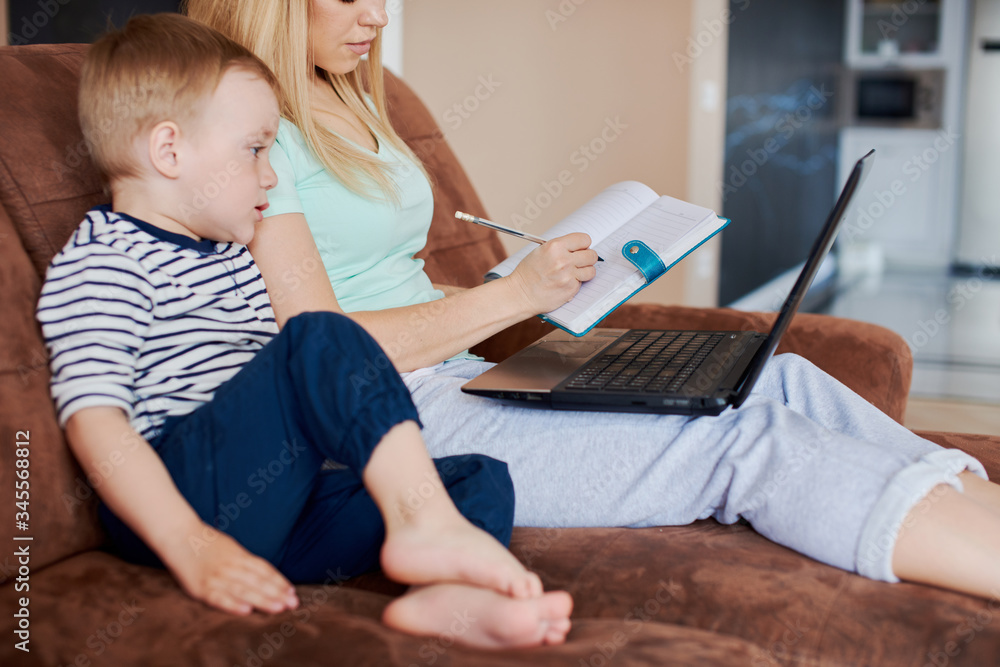 Mother and son drawing in notepad while using laptop