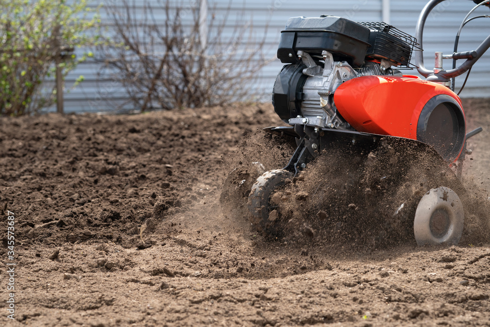 The cultivator digs the earth, clods of earth fly out from under the cultivator The cultivator digs the earth, clods of earth fly out from under the cultivator