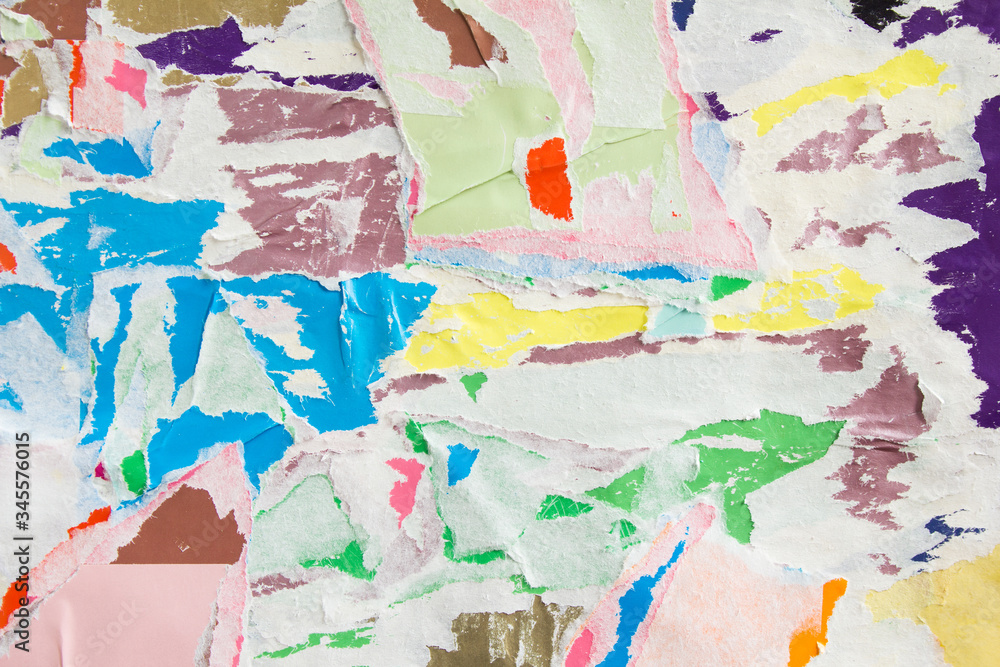 Colorful torn crumpled and peeling pieces of old paper layers on billboard. Bright motley abstract background.