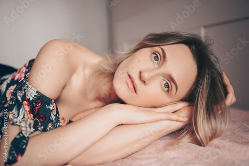Glamour fashion portrait of a beautiful smiling happy young woman lying on a bed