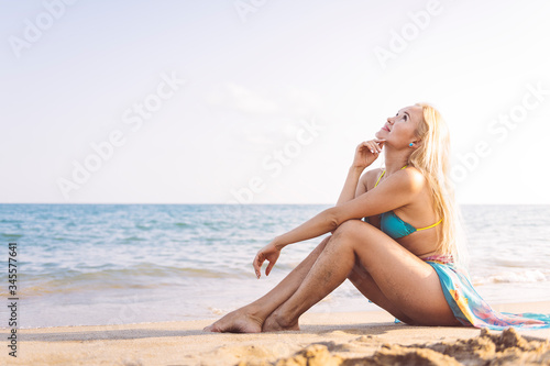 relaxed blonde girl sitting on the beach sand