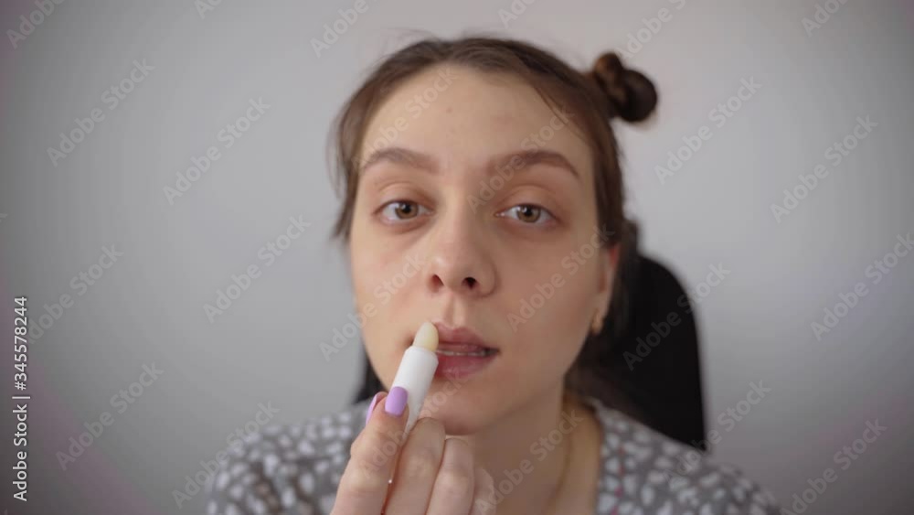 A young girl paints her lips with hygienic lipstick. Face care A young girl paints her lips with hygienic lipstick. Face care