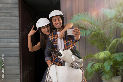 Canvas Print Young couple taking selfie sitting on motorbike
