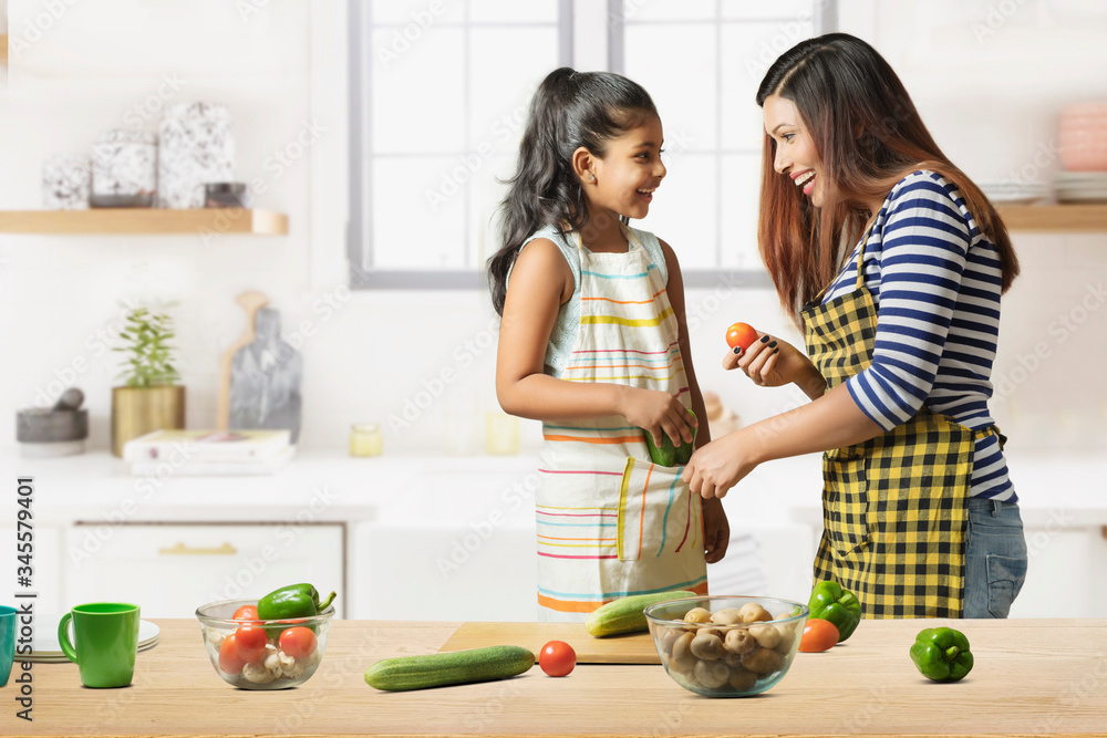 Mother and daughter making vegetable salad in kitchen
Mother and daughter making vegetable salad in kitchen