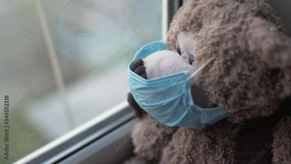 teddy bear in medical mask near window teddy bear in medical mask near window
