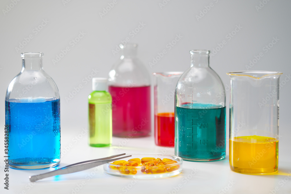 Glass bottles and flasks of different sizes with liquids of different colors on the background. Chemical lab. Glass bottles and flasks of different sizes with liquids of different colors on the background. Chemical lab.