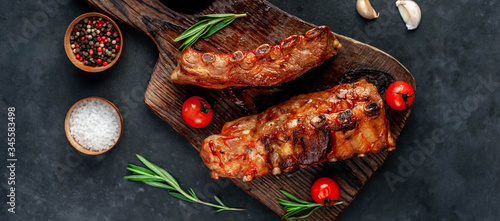 grilled pork ribs with spices and rosemary on a cutting board on a stone background