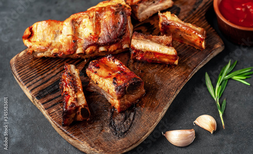 grilled pork ribs with spices and rosemary on a cutting board on a stone background