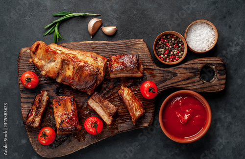 grilled pork ribs with spices and rosemary on a cutting board on a stone background
