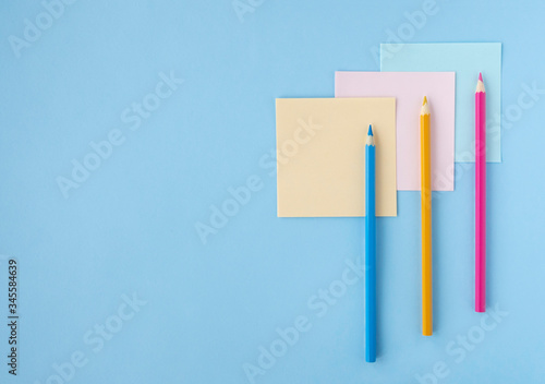 Flat lay with colored pencils and pieces of paper on blue background. Top view, copy space. Concept back to school, education, office
