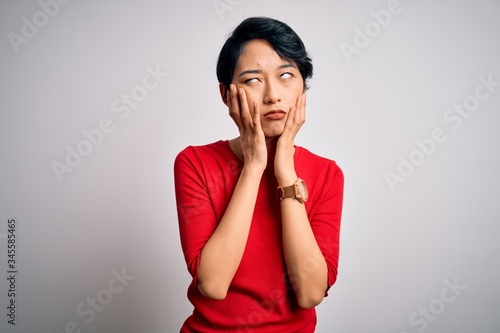 Young beautiful asian girl wearing casual red t-shirt standing over isolated white background Tired hands covering face, depression and sadness, upset and irritated for problem