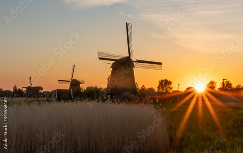 Holenderskie wiatraki nad kanałem wodnym, zachód słońca w Holandii Północnej photo