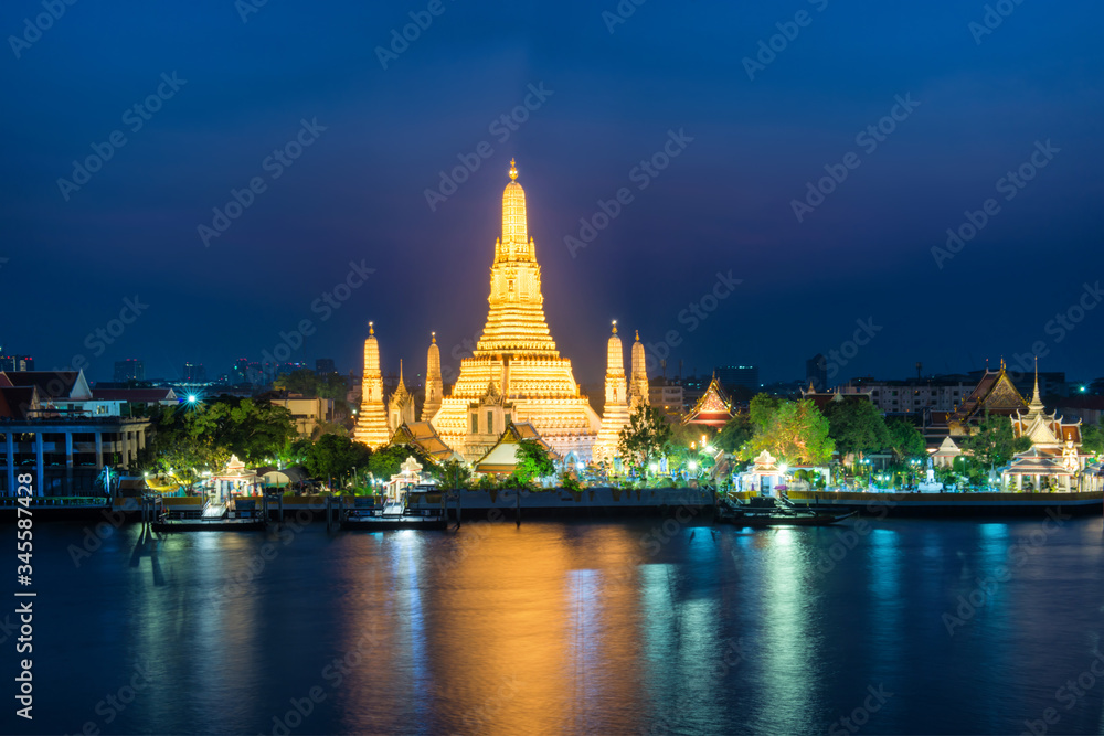 Night illuminated Temple of Dawn or Wat Arun and its reflection in Chao Phraya River at sunset. Bangkok, Thailand