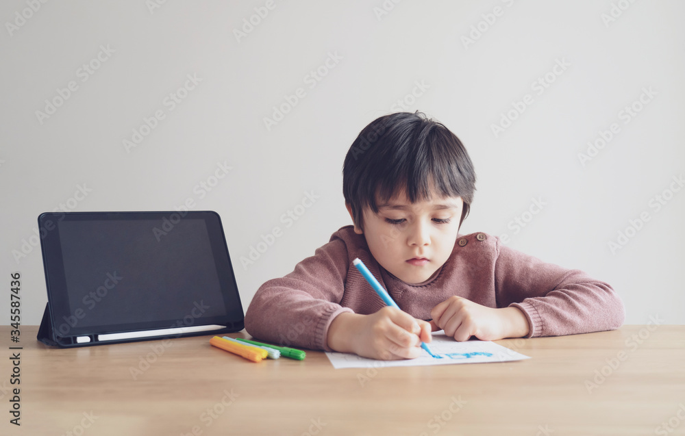 Kid self isolation using tablet for his homework,Child doing using digital tablet searching information on internet during covid 19 lock down,Home schooling,Social Distance,E-learning online education Kid self isolation using tablet for his homework,Child doing using digital tablet searching information on internet during covid 19 lock down,Home schooling,Social Distance,E-learning online education