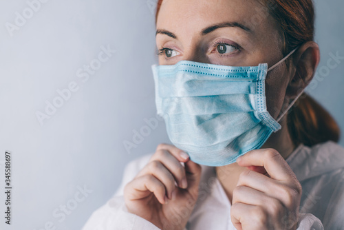 Female doctor puts on face mask. Close-up.