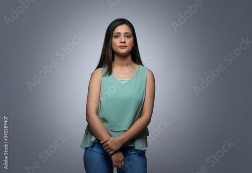Portrait of a teenage girl in jeans standing against grey background  © IndiaPix