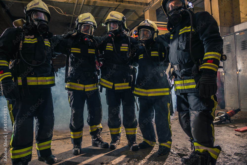 Team of firemen in uniform with gas masks inside the fire department Team of firemen in uniform with gas masks inside the fire department