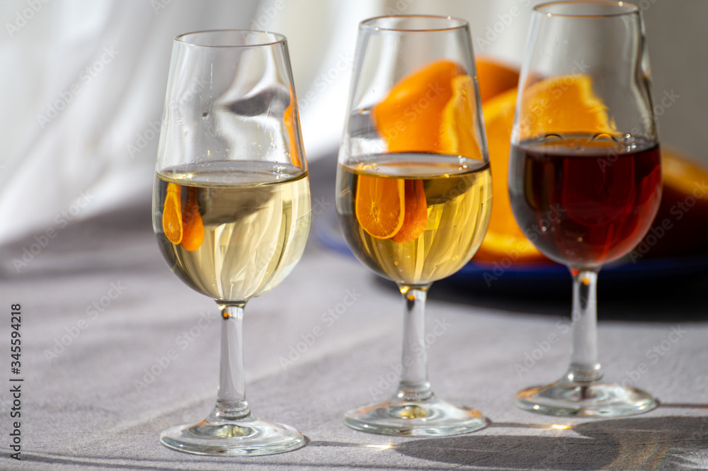 Glasses with cold dry fino and sweet cream sherry fortified wine in sunlights, andalusian style interior on background