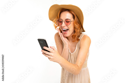 beautiful girl in a summer hat and sunglasses orders tickets on the phone on a white background © Ivan Traimak