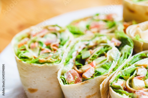 Pita rolls with tomatoes, green lettuce, cucumber and meat.