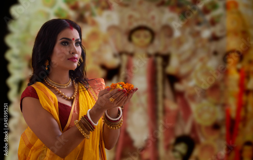 Portrait of a beautiful Married Bengali woman offering flowers , during Durga puja celebrations
 photo