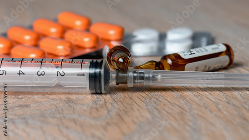 Syringe, ampoules and pills on the table close-up. Concept of a vaccine against coronavirus infection.