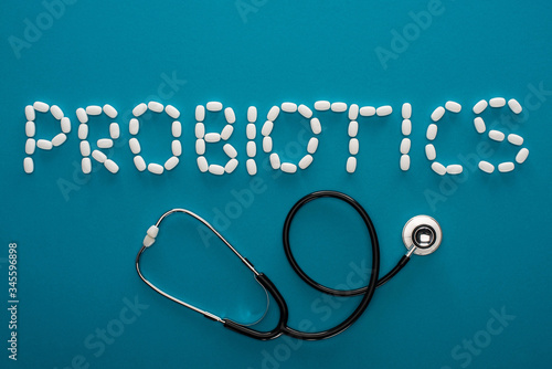 top view of probiotics lettering made of pills and stethoscope on blue background
