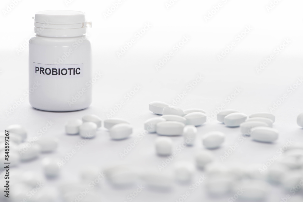 selective focus of probiotic container near pills on white background selective focus of probiotic container near pills on white background