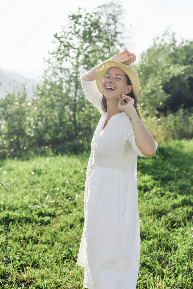 a happy girl in a hat walks through a field of daisies