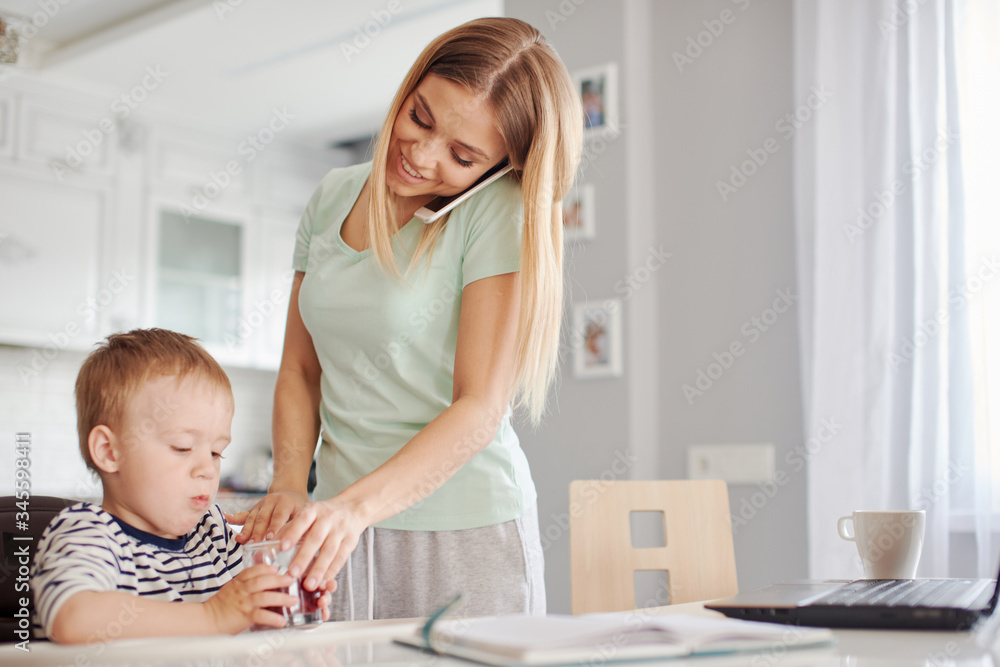Busy mother feeding child and talking on the phone Busy mother feeding child and talking on the phone