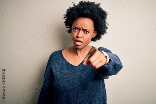 Young beautiful African American afro woman with curly hair wearing casual sweater pointing displeased and frustrated to the camera, angry and furious with you