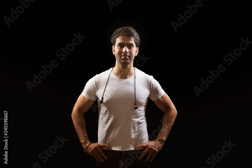 Young man standing with his hands on hips looking at camera 