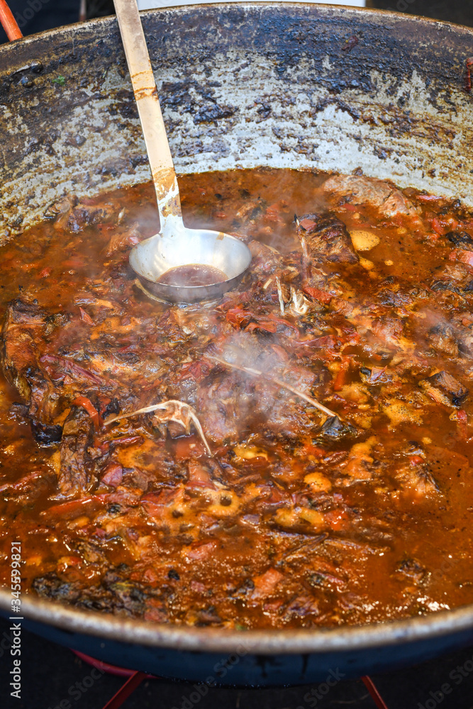 Fototapeta premium Traditional fish stew being prepared in a rustic bowl over a wood background.