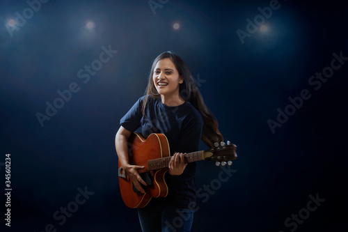 young Woman playing guitar on stage
