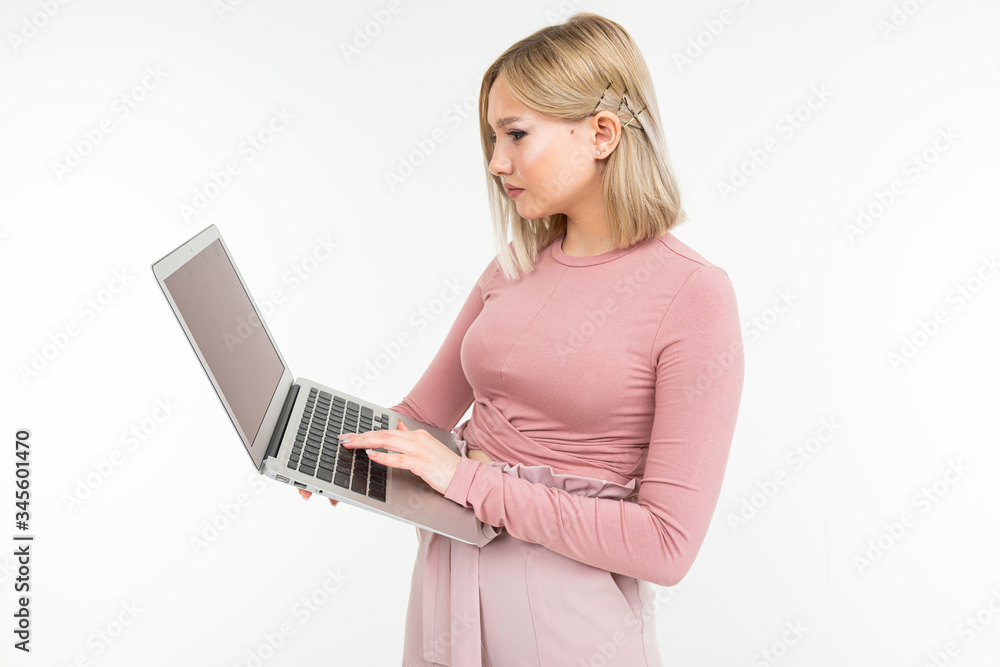 attractive blonde girl is typing on a laptop keyboard on a white studio background attractive blonde girl is typing on a laptop keyboard on a white studio background