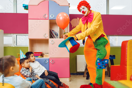 Print op canvas Funny clown shows tricks to surprised children