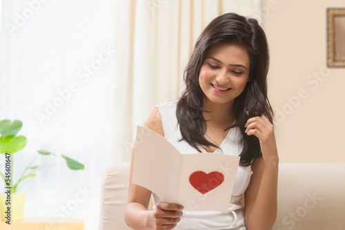 Woman reading romantic Valentine card at home
