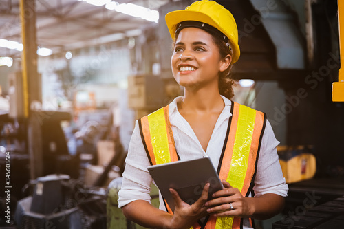 Industry maintenance engineer woman dark skin wearing uniform and safety helmet under inspection and checking production process on factory station by tablet. Industry, Engineer, construction concept.