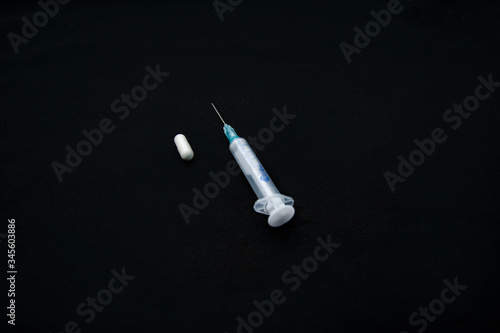 syringe and pills on black background