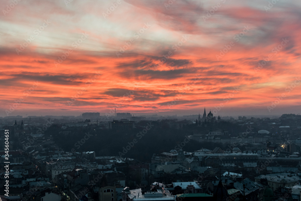 Beautiful, orange, fiery sunset over Lviv city in Ukraine. Cityscape with skyline and clouds. Town, buildings, towers, church and amazing sky.