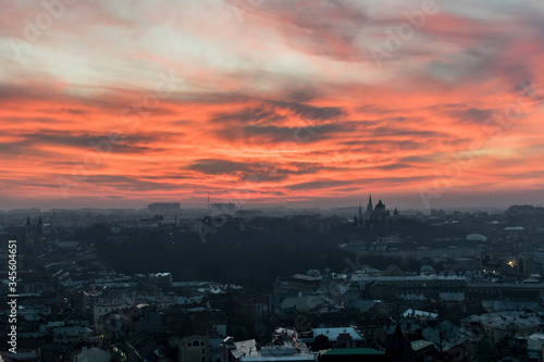 Beautiful, orange, fiery sunset over Lviv city in Ukraine. Cityscape with skyline and clouds. Town, buildings, towers, church and amazing sky. © Tomasz
