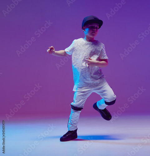 Cool young boy child dancing hip hop in the Studio against the background of neon lights. Break dance poster.