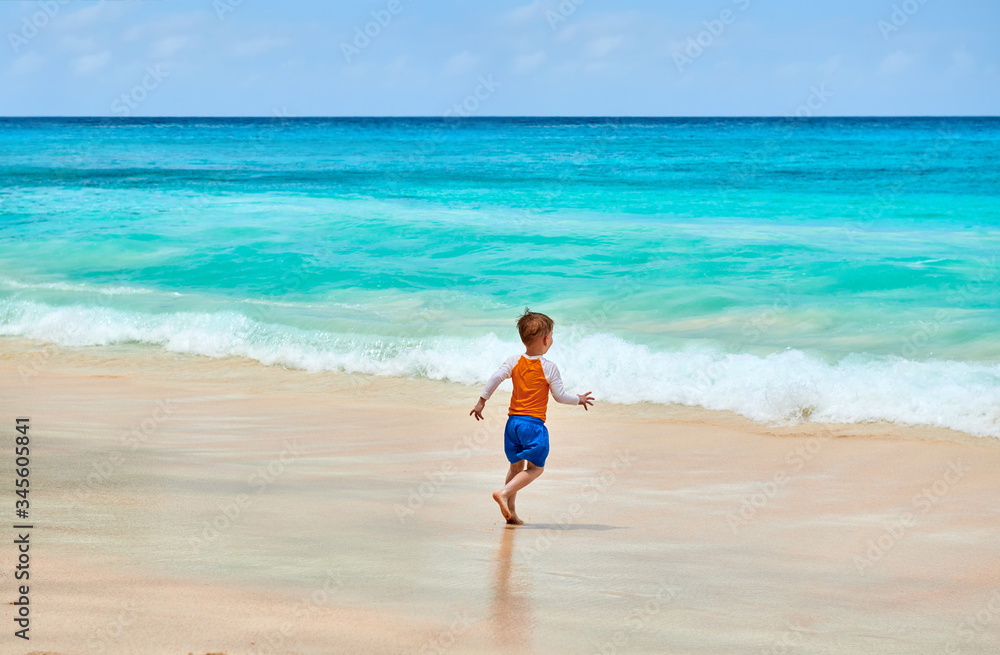 Three year old toddler boy running on beach